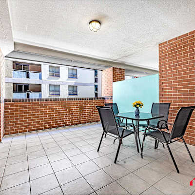 Private covered balcony with outdoor table and chairs, surrounded by brick walls.