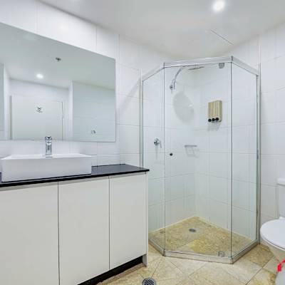 Modern bathroom with glass shower enclosure, vanity with storage, and toilet.