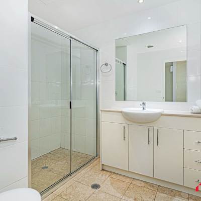Modern bathroom with glass shower enclosure, vanity with storage, and toilet.