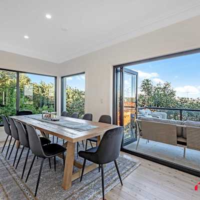 Dining area with large table and sliding doors opening to the balcony with water views.