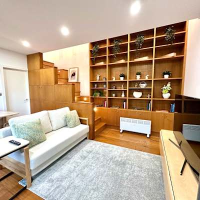 Living area with built-in shelving, sofa seating, and warm timber flooring.
