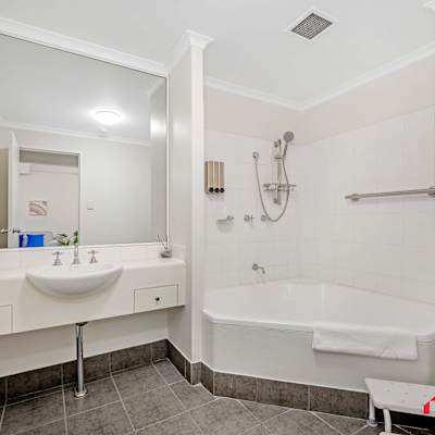 Accessible bathroom with vanity, shower area, and handrail support.