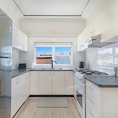 Main kitchen with ample cabinetry, oven, cooktop, and natural light.