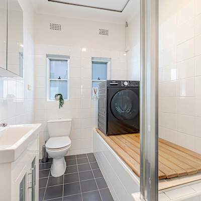 Bathroom with vanity, shower, toilet, and washing machine.