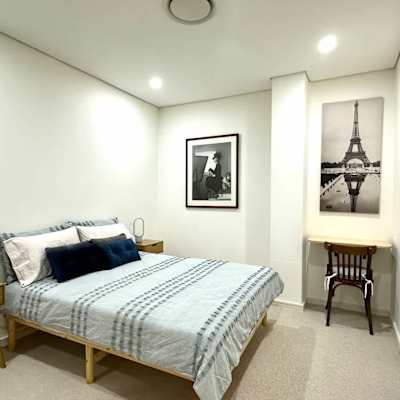 Bedroom featuring a double bed, bedside table, wall art, and study desk.