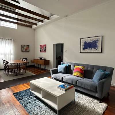 Living room with sofa seating, coffee table, timber flooring, and exposed ceiling beams.