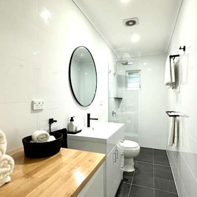 Bathroom with vanity, round mirror, shower area, and fresh towels.