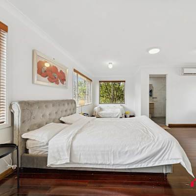 Alternate bedroom view showcasing the queen-sized bed, bedside table, and natural light from the windows.