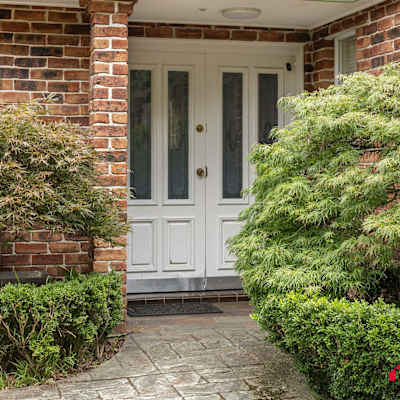 Welcoming front entrance with brick façade and garden landscaping.