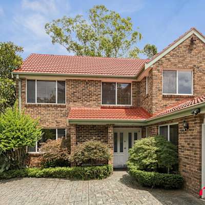 Front exterior of a two-storey brick home with landscaped garden and driveway.