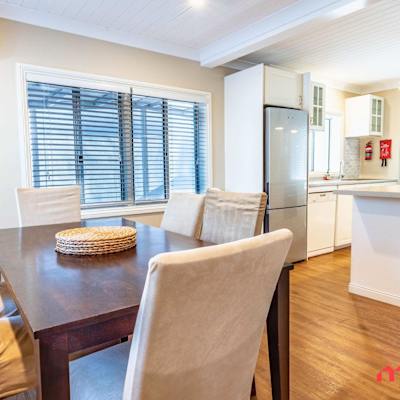 Dining area with wooden table and upholstered chairs beside the kitchen.