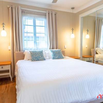 Spacious bedroom featuring a king-sized bed, mirrored built-in wardrobe, and bedside lighting.