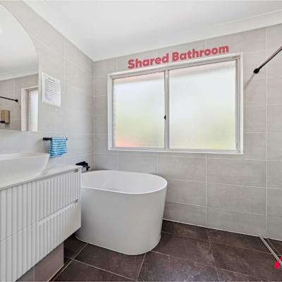 Shared bathroom with freestanding bathtub, glass shower, and vanity.