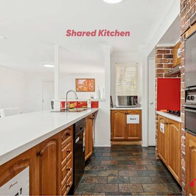 Shared kitchen with long white countertop, wooden cabinetry, and modern appliances