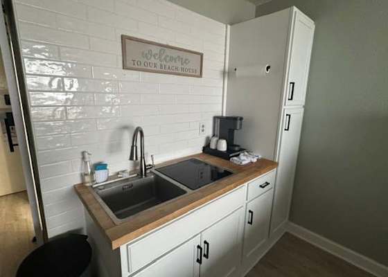 Modern kitchenette equipped with a coffee maker, sink, cooktop, and generous pantry storage
