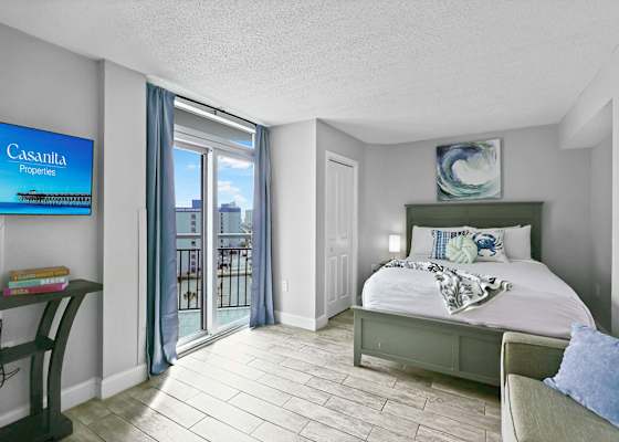 Relax in this serene coastal bedroom featuring a comfy bed, stylish decor, smart TV, and private balcony access. The perfect blend of comfort and charm for your Myrtle Beach escape!
