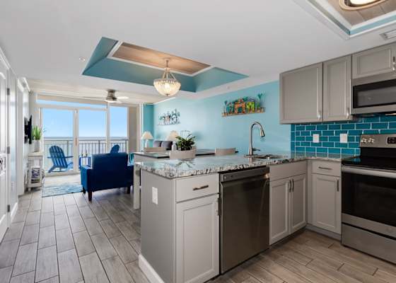 Cook and entertain in style with this open-concept kitchen featuring sleek stainless steel appliances, granite countertops, and vibrant coastal accents. Overlooking the living area and balcony, it's perfect for enjoying meals with ocean views.
