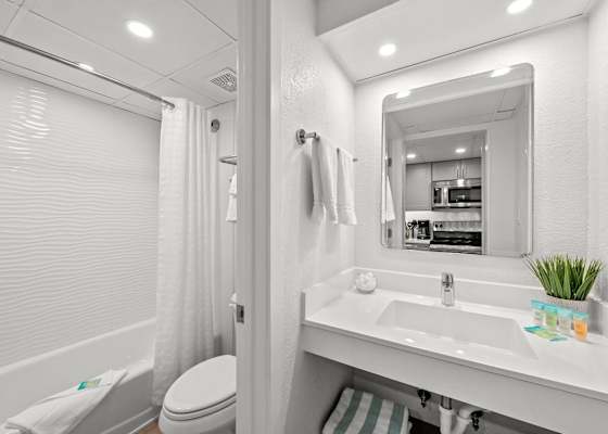 Freshen up in this bright, modern bathroom featuring sleek finishes, soft lighting, and a relaxing tub—perfect for unwinding after a day at the beach.