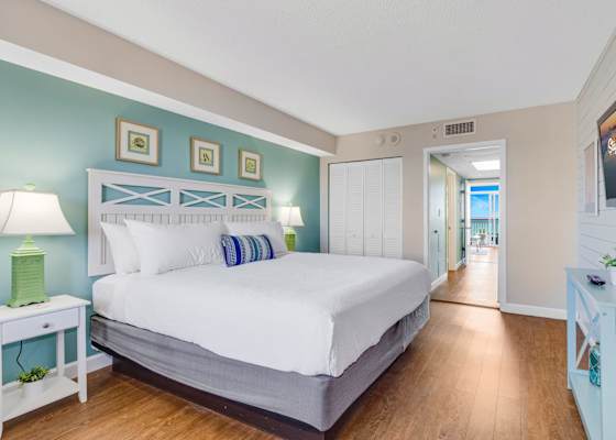 Relax in style in this serene bedroom featuring a plush king-sized bed, soothing coastal decor, and ample natural light. Drift off to the sound of the waves and wake up refreshed, just steps away from breathtaking ocean views. 