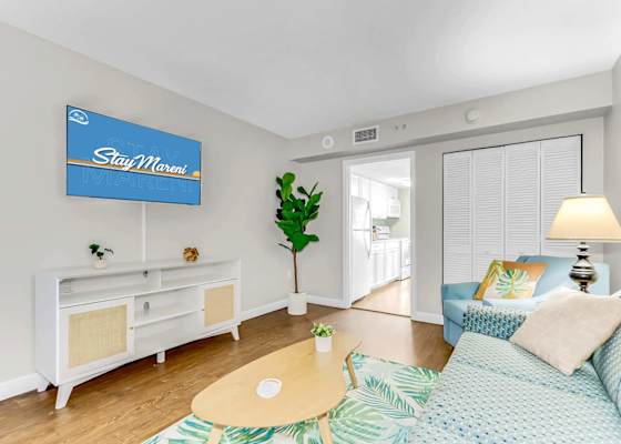Unwind in this cozy and bright living room featuring tropical decor, a comfy seating area, and a flat-screen TV. Perfect for relaxing after a day of adventure, with a seamless flow to the fully equipped kitchen for ultimate convenience.