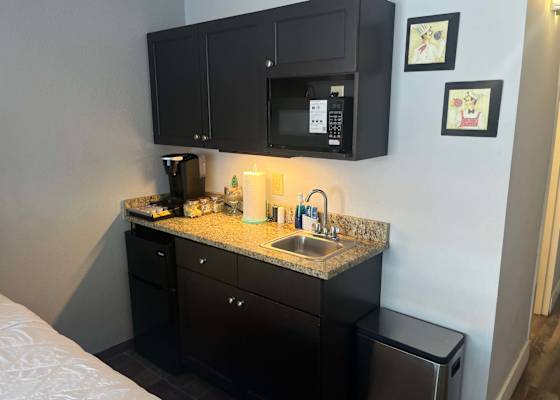 Compact kitchenette station equipped with a microwave, coffee maker, sink, and mini fridge