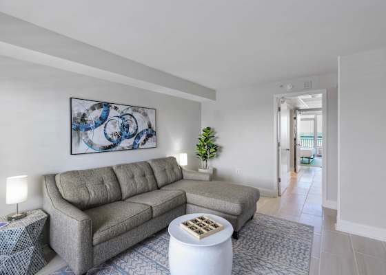 Cozy up in this chic coastal living space featuring a comfy sectional, playful decor, and a peek into your ocean-view bedroom—perfect for relaxing after a beach day or enjoying a game night in.