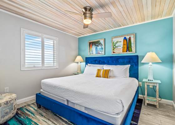Unwind in this cozy bedroom featuring a plush king-sized bed, nautical-inspired decor, and a ceiling fan for added comfort. Wake up refreshed with natural light and glimpses of the ocean just outside your window—your perfect seaside retreat!