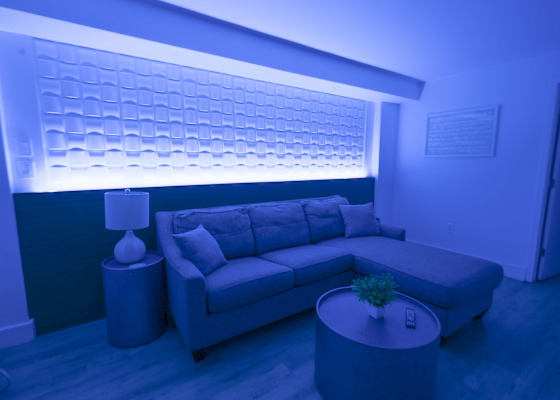 Ambient LED lighting, sectional sofa, and a textured feature wall—perfect for relaxing in a stylish, cozy atmosphere.