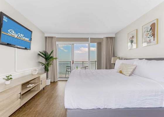 Wake up to breathtaking ocean views in this modern, serene bedroom featuring a plush king-size bed, stylish decor, and direct access to a private balcony. Relax in comfort with a flat-screen TV and soothing natural tones of the waves from the ocean.