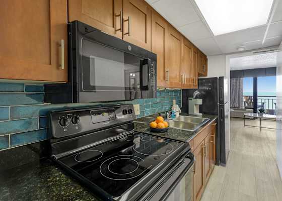 Cook with a view in this fully equipped kitchen featuring granite countertops, modern appliances, and a stylish backsplash. Whether it's breakfast or a beach day snack, everything you need is just steps from the ocean.