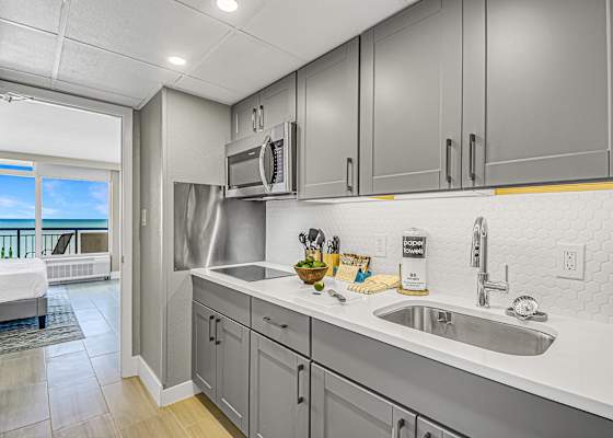 Modern kitchen with sleek cabinetry and a stylish blue-tile backsplash, fully equipped for your culinary needs. Just steps from the bedroom, this space offers convenience and functionality, allowing you to enjoy meals with a stunning ocean view.