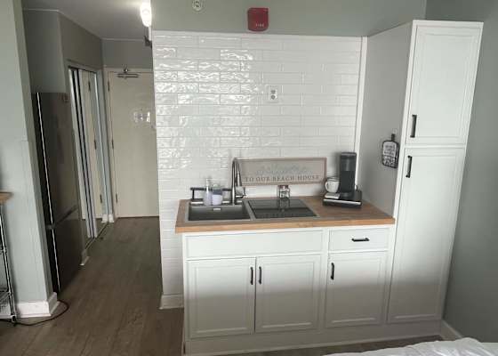 Modern kitchenette equipped with a coffee maker, sink, cooktop, and generous pantry storage