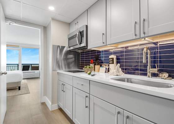 Modern kitchen with sleek cabinetry and a stylish blue-tile backsplash, fully equipped for your culinary needs. Just steps from the bedroom, this space offers convenience and functionality, allowing you to enjoy meals with a stunning ocean view.