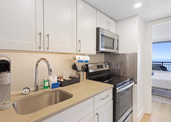 Modern kitchen with stainless steel appliances and ocean views from the bedroom beyond.