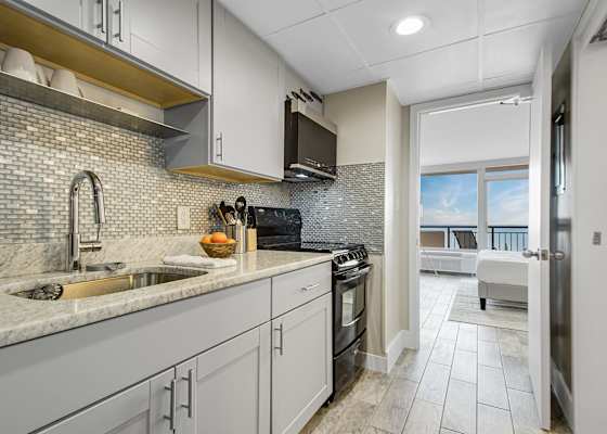 Modern kitchen with sleek cabinetry and a stylish blue-tile backsplash, fully equipped for your culinary needs. Just steps from the bedroom, this space offers convenience and functionality, allowing you to enjoy meals with a stunning ocean view.