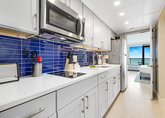 Modern kitchen with stainless steel appliances, quartz countertops, and ocean views. 
