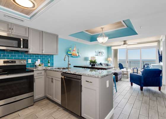 Whip up your favorite meals in this beautifully designed kitchen, featuring modern appliances, stunning blue accents, and granite countertops. Whether cooking or relaxing in the cozy living area with ocean views, this space offers the perfect blend.