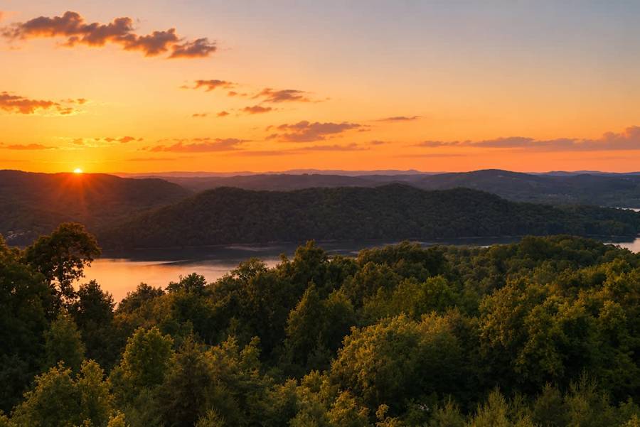 The sun setting orange over Norris Lake and forested hills, seen from the cabin