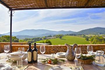 Glasses with wine and water jug on a table with view of hills