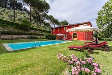 Red house next to a swimming pool and grass