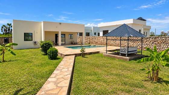 Garden path towards the bungalow, with the pool and shaded outdoor seating to the right.