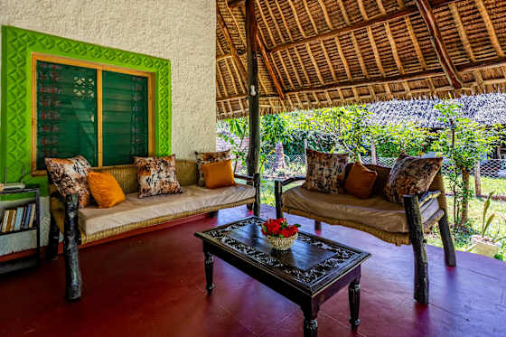 Cushioned veranda seating and a glass-topped coffee table beside the garden.