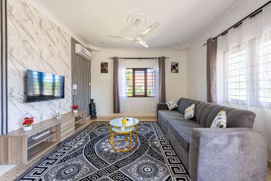 The apartment’s living room has a corner sofa, television and a patterned rug.
