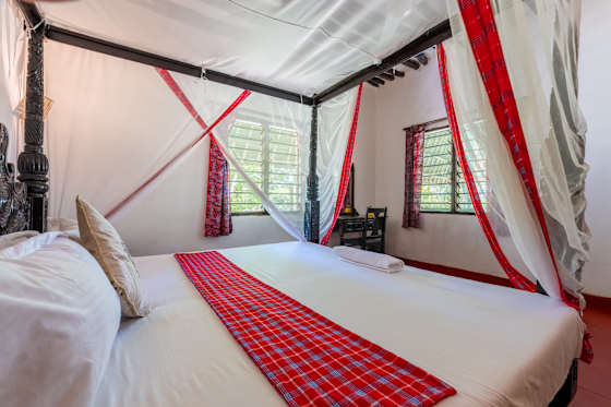 Bedroom 2 with a king bed, white bedding and a mosquito net.