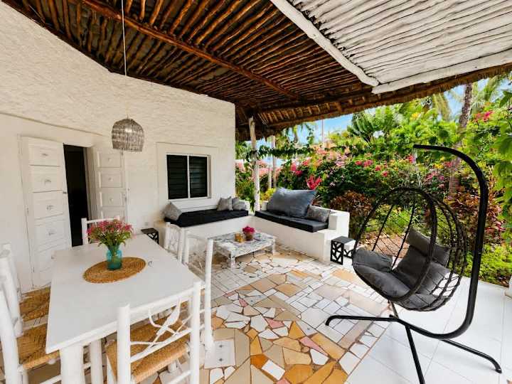 Cali Blossom’s covered veranda, with a hanging chair, cushioned sofas and outdoor dining.