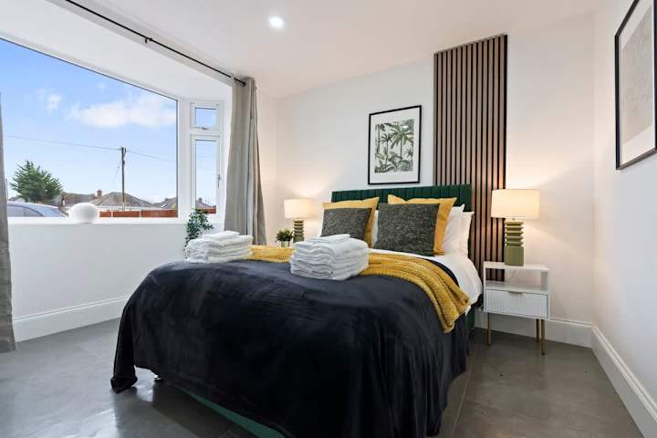 A bedroom with a double bed, a window, and a cupboard for storage.