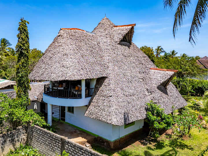 Villa Boba beneath its traditional makuti roof, surrounded by tropical greenery.