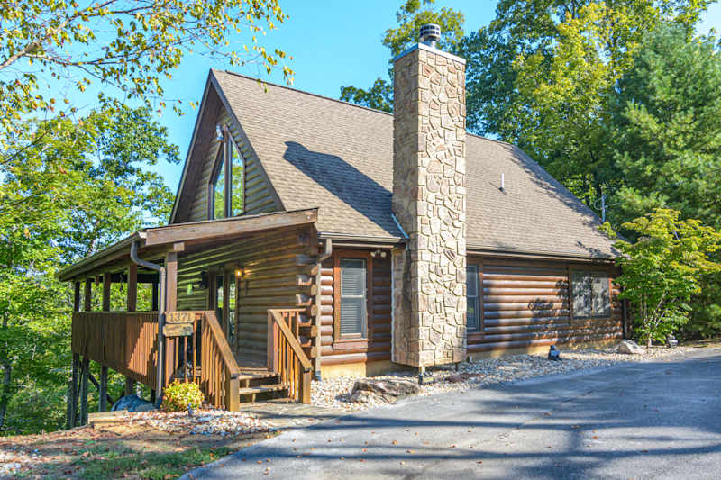 Loving Life log cabin exterior with covered porch and stone chimney