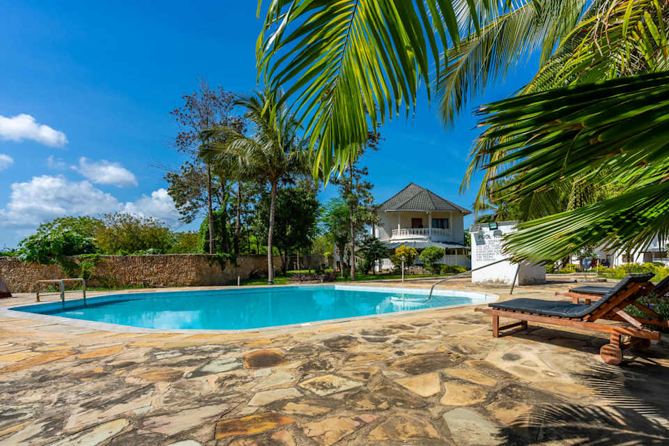 The Orchard’s shared swimming pool, with a stone terrace and tropical garden surroundings.