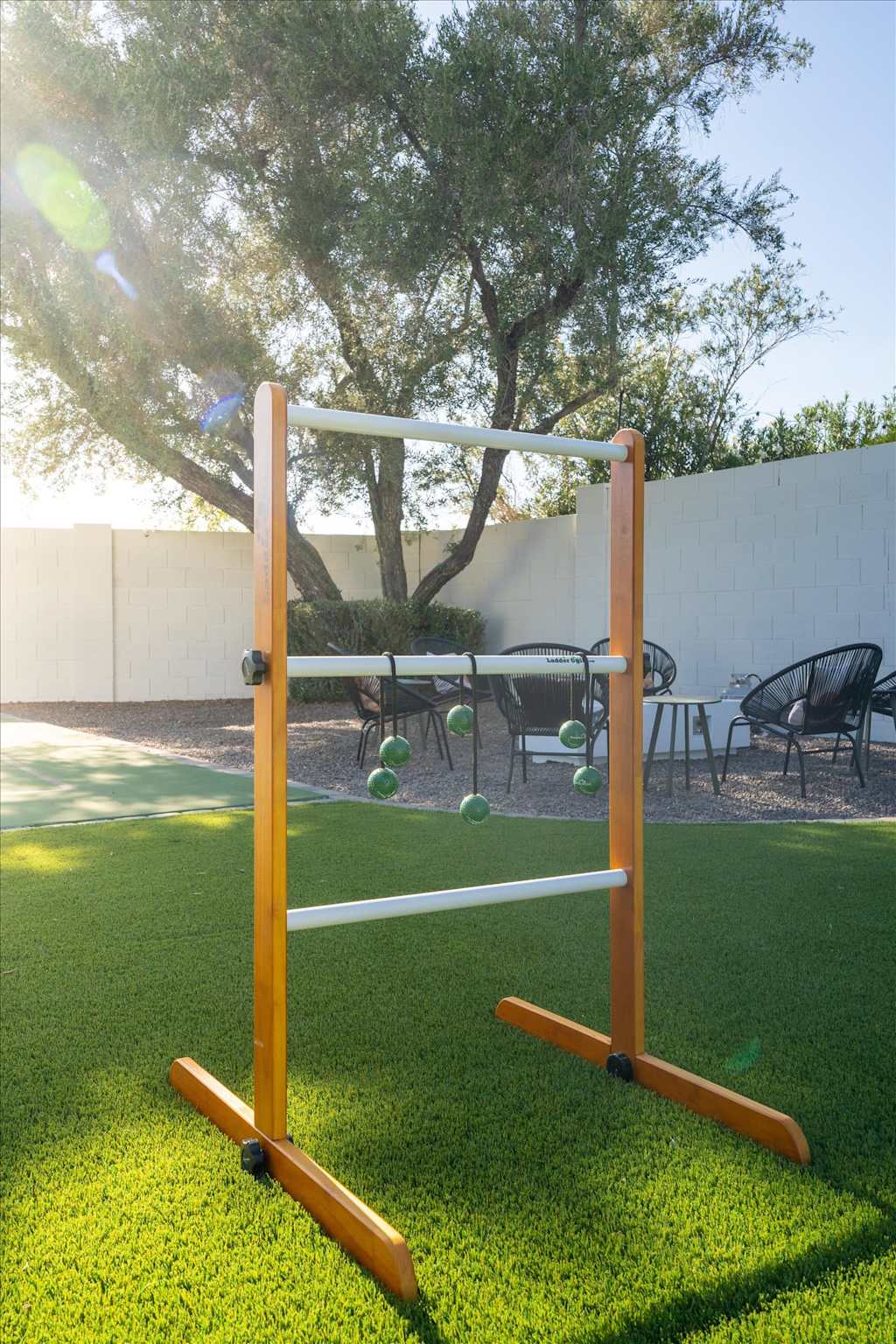 The Sunkiss — ladder toss lawn game on artificial grass in a backyard with seating in the background